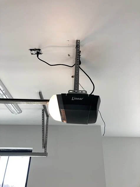 West County Garage Door Service opener install A garage door opener is mounted to the ceiling, but it is installed incorrectly, hanging upside down with exposed wiring and metal brackets.