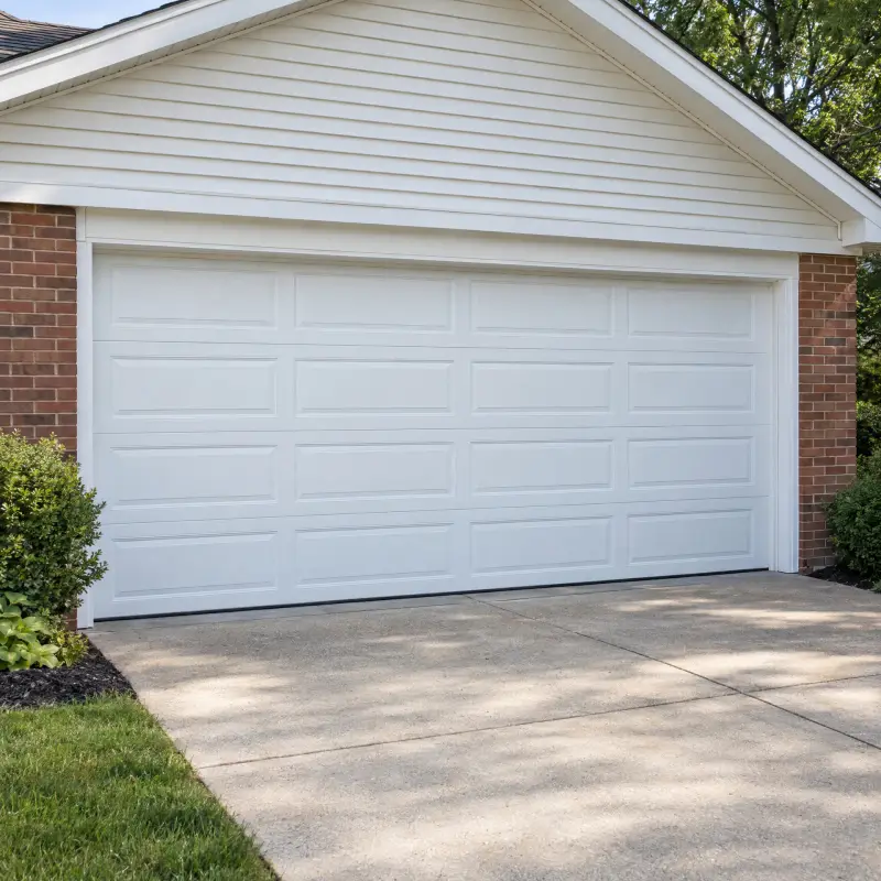 White sectional garage door on a brick house with a concrete driveway.